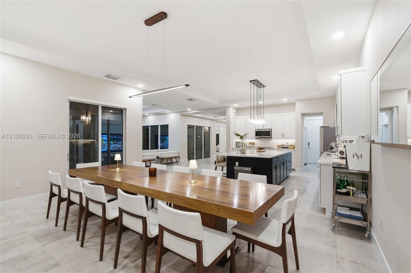 15215 SW 176th Lane, Miami, FL 33187 Open concept kitchen and dining area featuring large format tile flooring, a central kitchen island with contrasting cabinetry, white shaker-style wall cabinets, and recessed lighting