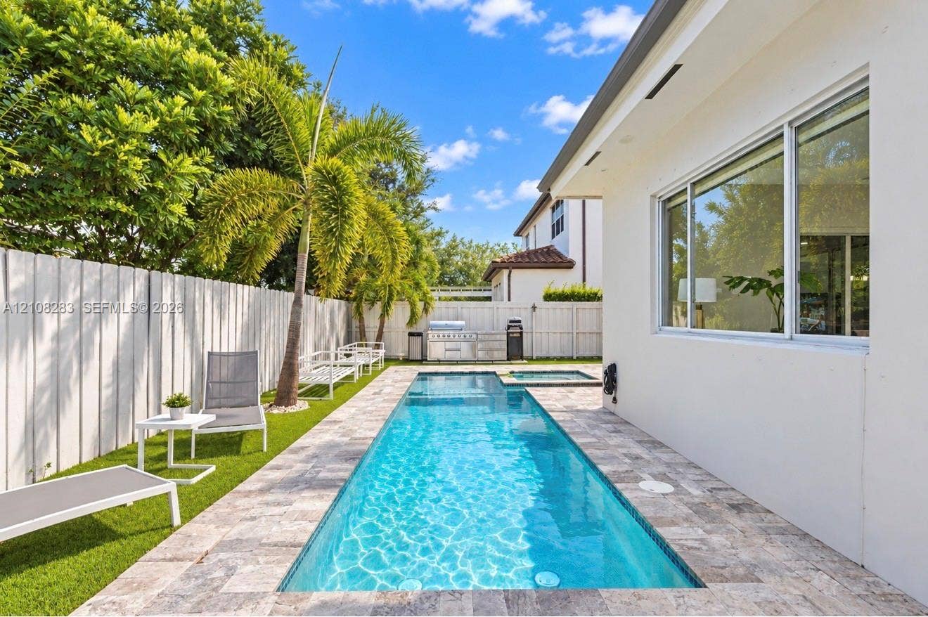 15215 SW 176th Lane, Miami, FL 33187 Private backyard featuring an inground lap pool, integrated spa, stone-finish decking, artificial turf, and a perimeter privacy fence