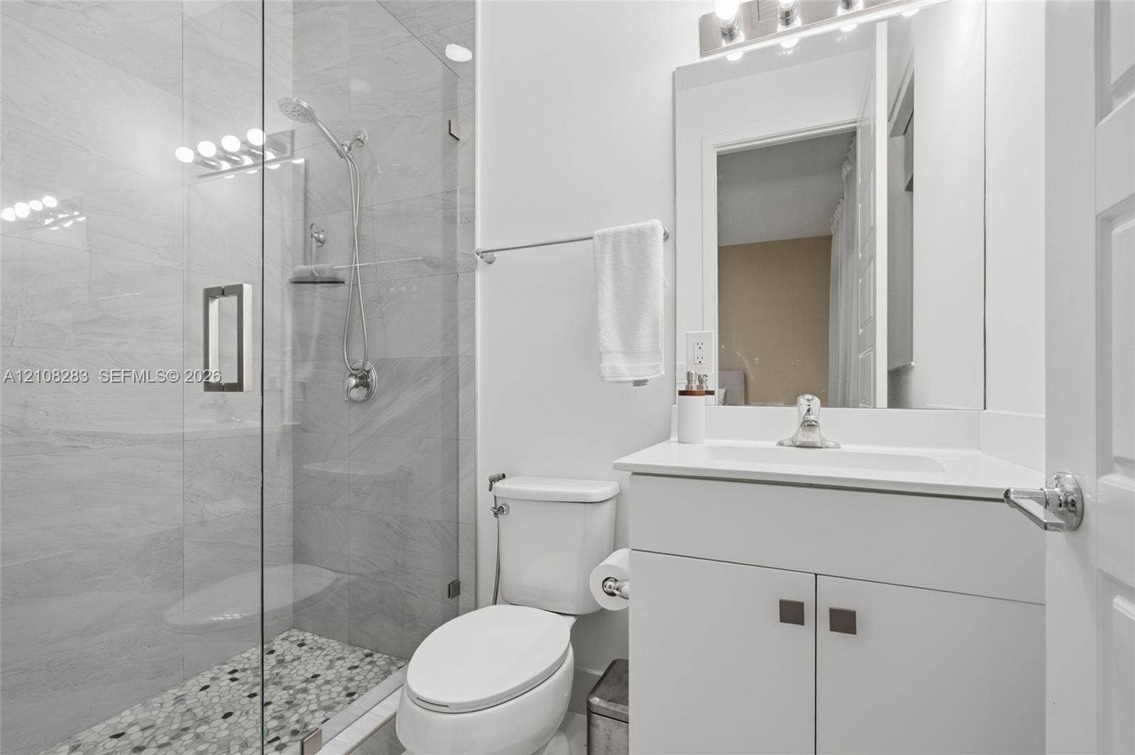 15215 SW 176th Lane, Miami, FL 33187 Glass-enclosed shower with stone-tile flooring, wall-mounted handheld shower head, vanity with integrated basin, and modern light fixture