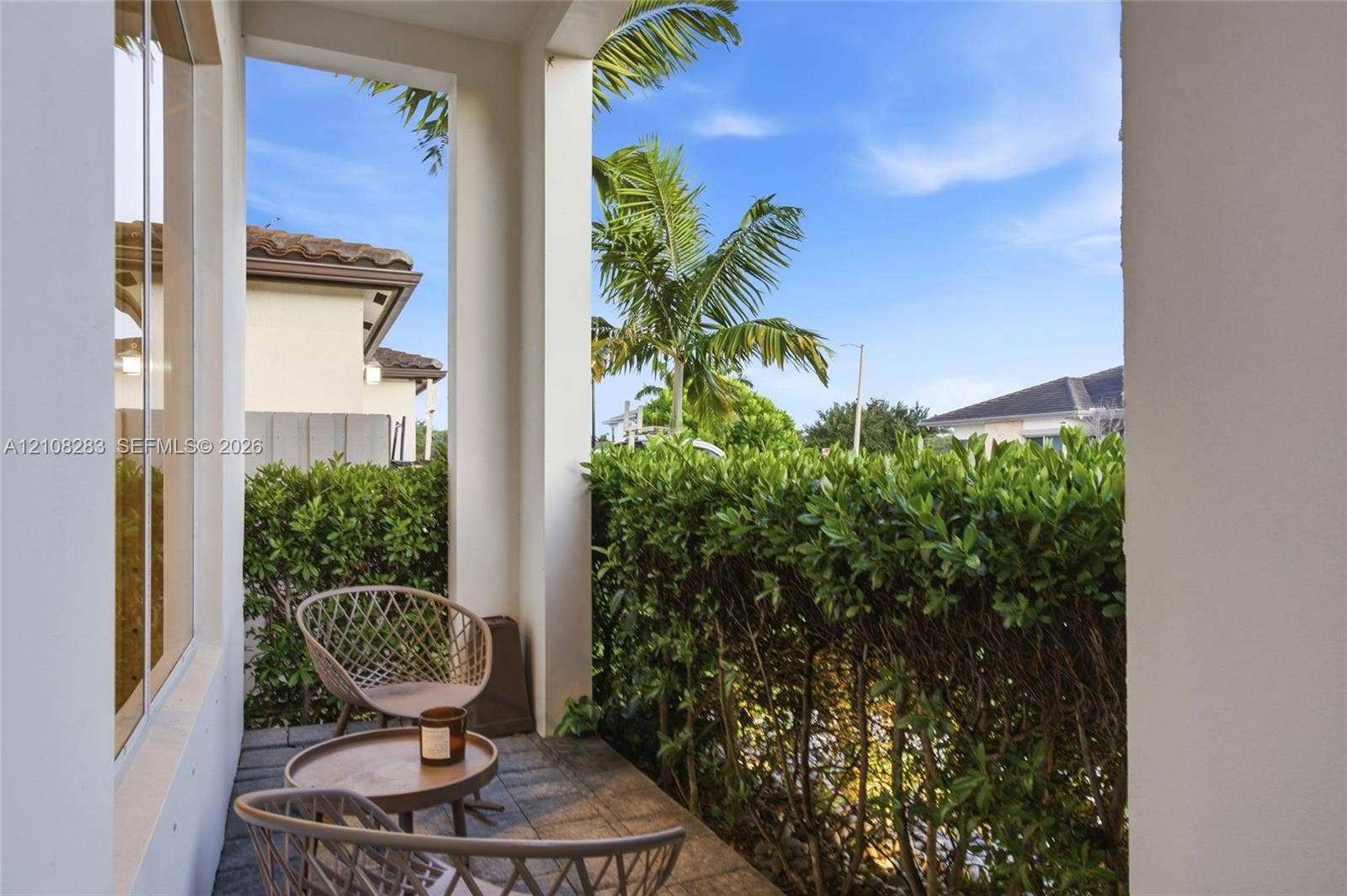 15215 SW 176th Lane, Miami, FL 33187 Covered patio featuring stone-tile flooring, structural support columns, and dense, manicured privacy hedging