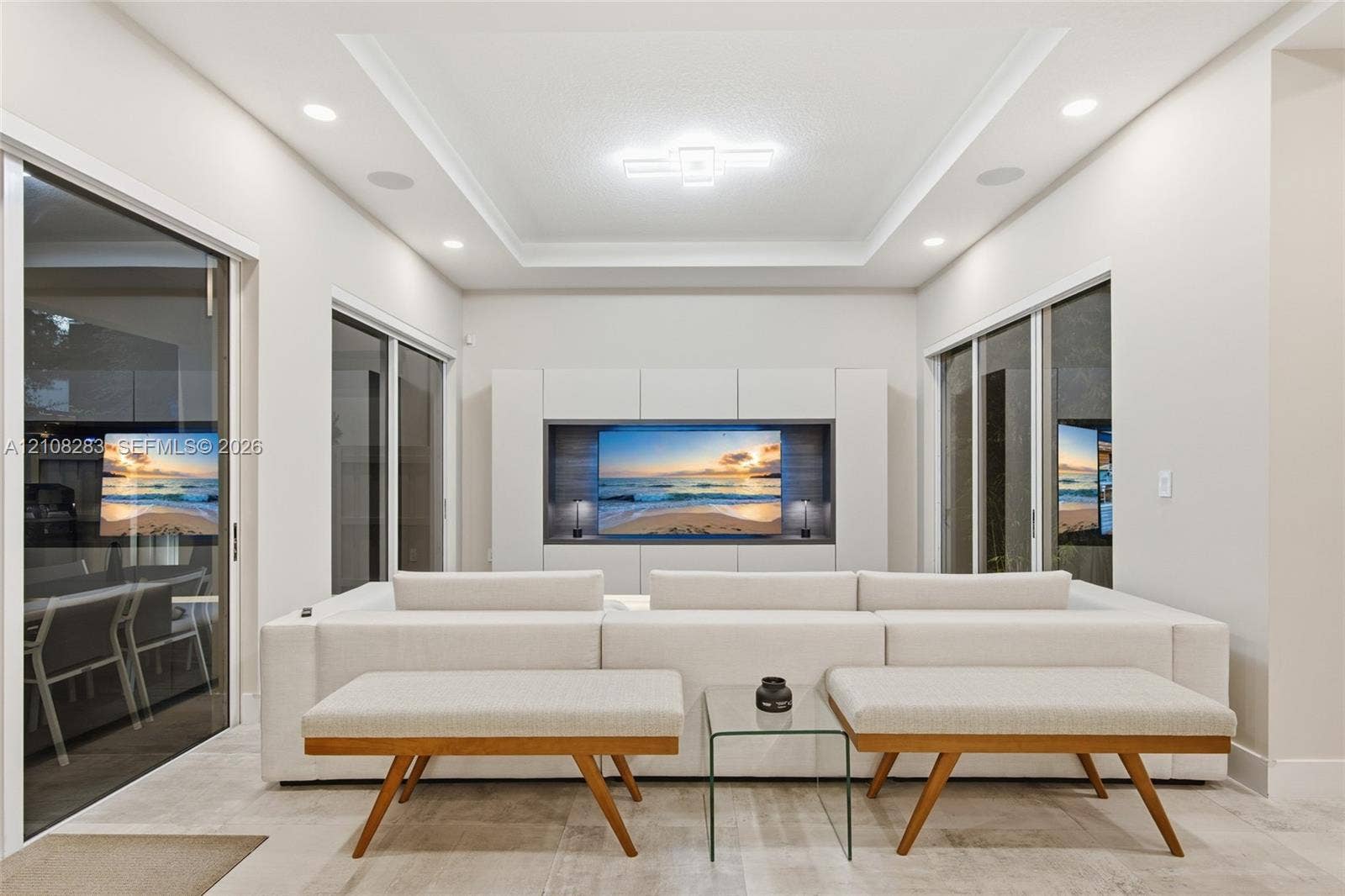 15215 SW 176th Lane, Miami, FL 33187 Living space featuring a tray ceiling, recessed lighting, large-format tile flooring, built-in media cabinetry, and multiple sliding glass doors
