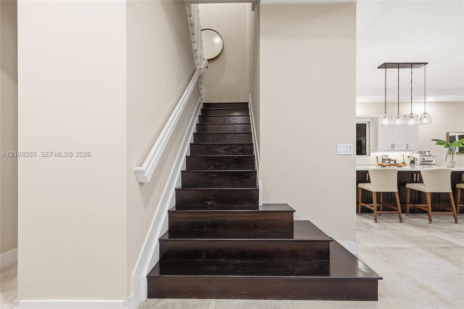 15215 SW 176th Lane, Miami, FL 33187 Staircase featuring dark wood-finish treads, white handrail, and white balusters, situated on stone-finish flooring with a multi-pendant light fixture and built-in cabinetry in the background