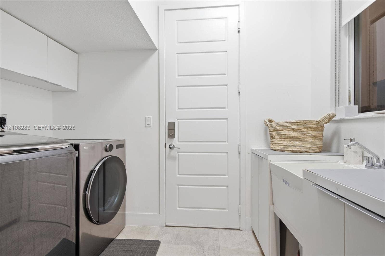 15215 SW 176th Lane, Miami, FL 33187 Laundry area featuring white cabinetry, a utility sink with a faucet, five-panel door, and tiled flooring