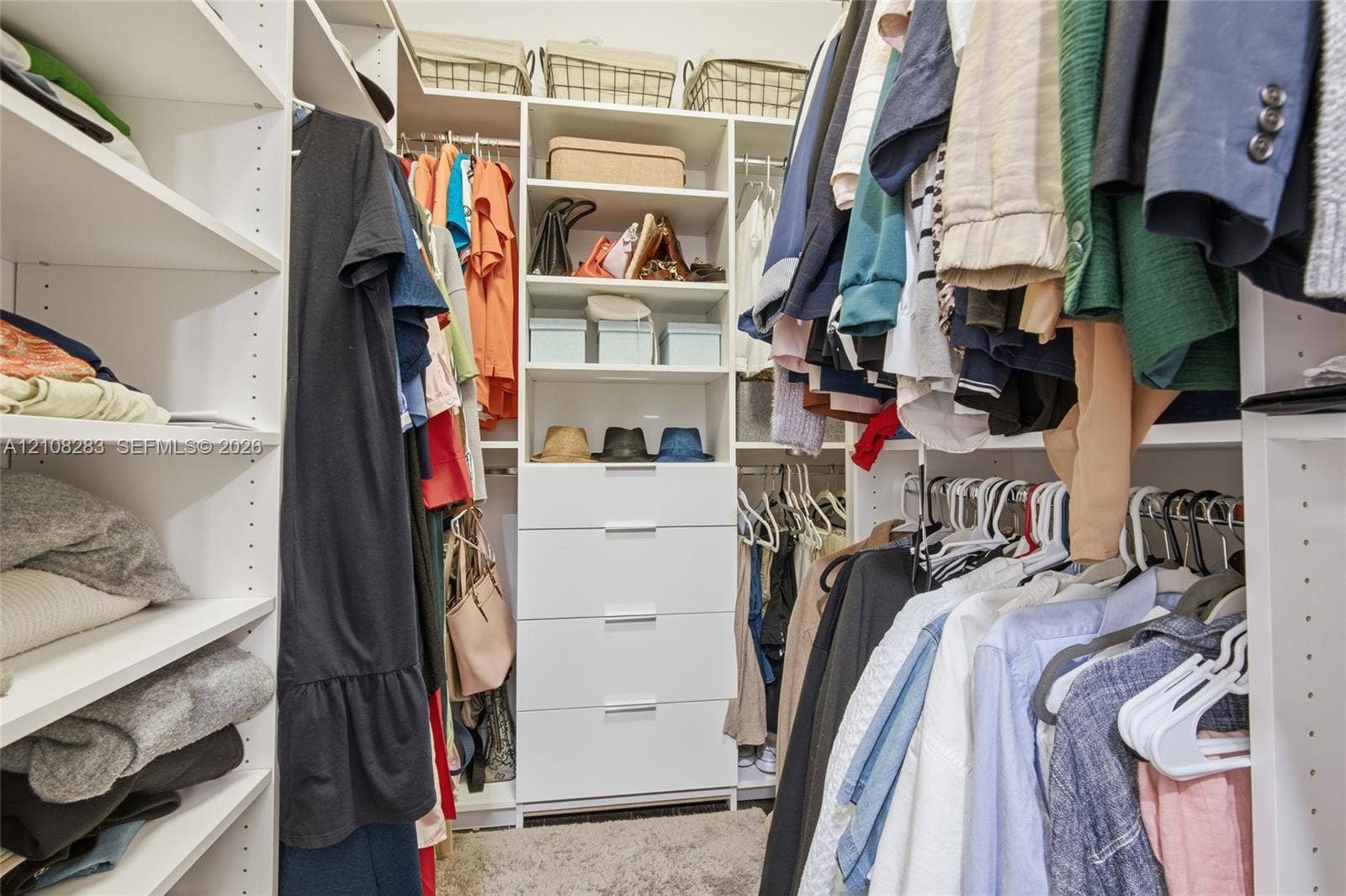 15215 SW 176th Lane, Miami, FL 33187 Walk-in closet featuring white custom built-in shelving, a central column of four soft-close drawers with metallic pulls, and multi-level hanging rods