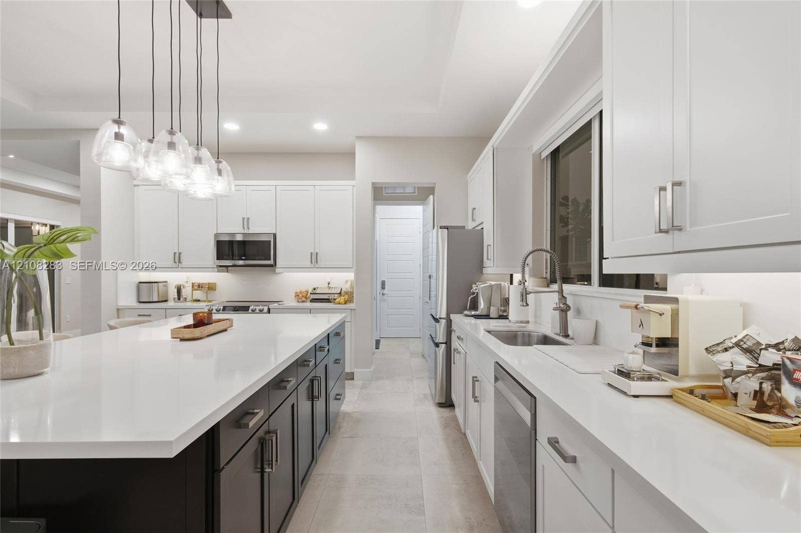 15215 SW 176th Lane, Miami, FL 33187 Kitchen featuring a central island with a solid-surface countertop, white shaker-style cabinetry, stainless steel appliances, and multi-light pendant fixture