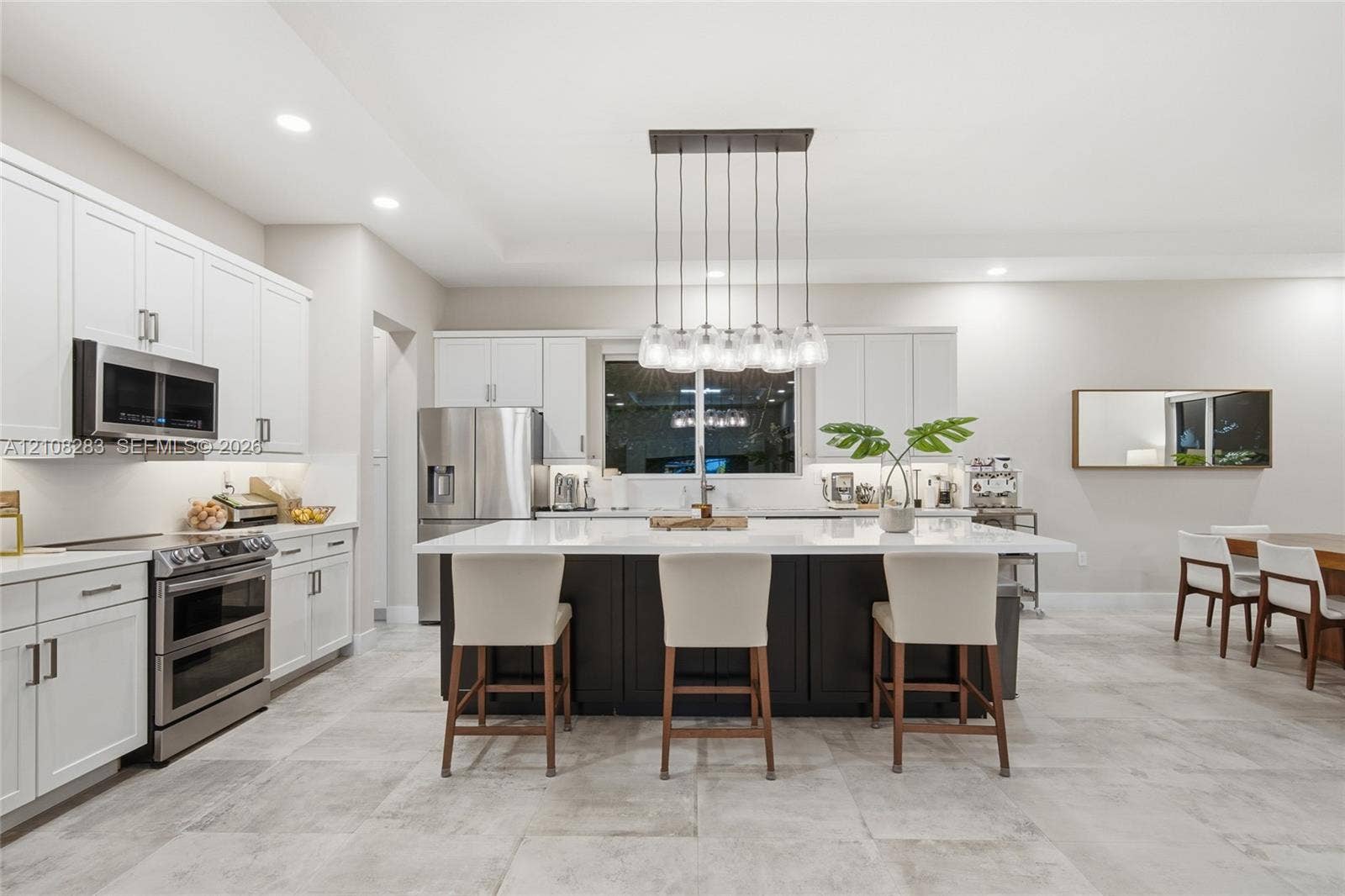 15215 SW 176th Lane, Miami, FL 33187 Kitchen featuring white shaker-style cabinetry, a contrasting dark-toned kitchen island with a light-toned solid surface countertop, stainless steel appliances, and tile flooring