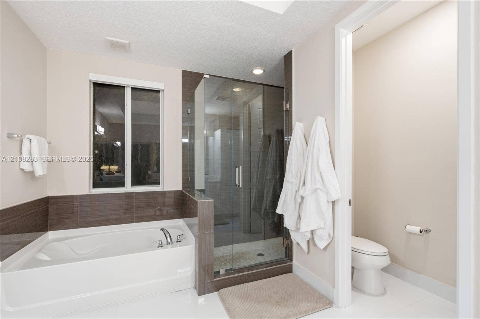 15215 SW 176th Lane, Miami, FL 33187 Built-in soaking tub with a tiled surround, glass-enclosed shower, polished finish flooring, and wall-mounted metal fixtures
