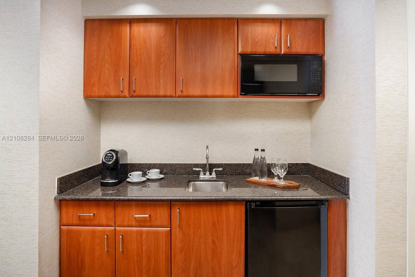 18001 Collins Avenue, #908, Sunny Isles Beach, FL 33160 Wet bar featuring wood-finish cabinetry, stone countertop, stainless steel drop-in sink, and built-in microwave