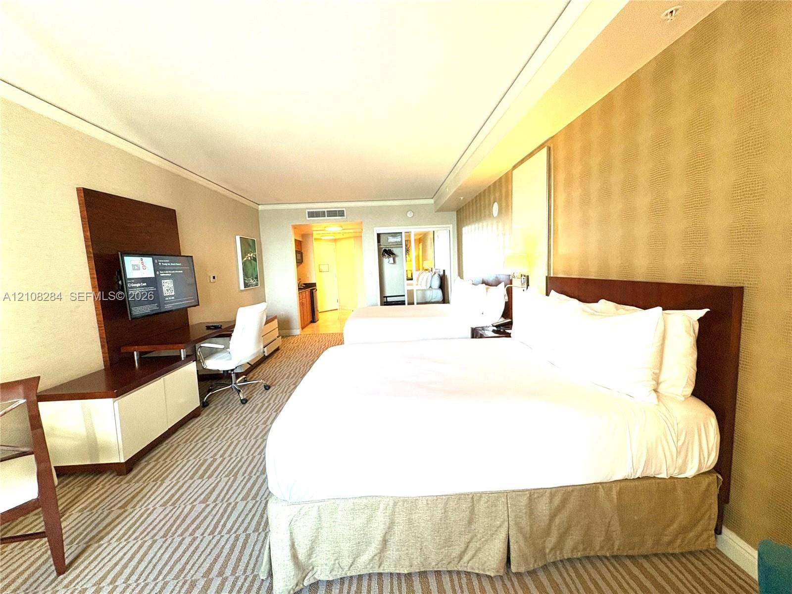 18001 Collins Avenue, #908, Sunny Isles Beach, FL 33160 Spacious room featuring patterned carpeting, recessed ceiling lighting, textured wall coverings, and integrated media cabinetry with a built-in workspace