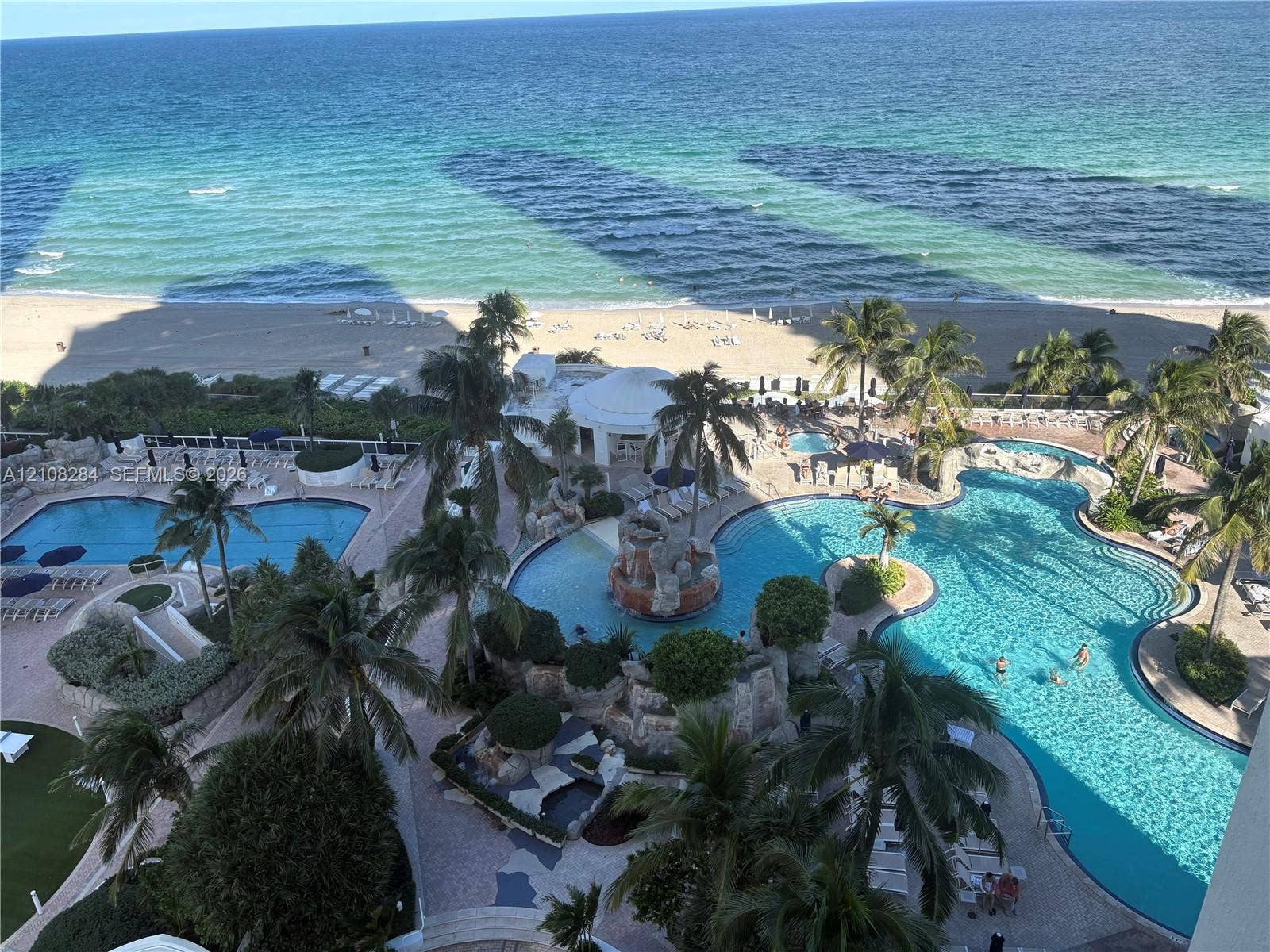 18001 Collins Avenue, #908, Sunny Isles Beach, FL 33160 Oceanfront property featuring multiple resort-style swimming pools, rock-feature waterfalls, landscaped tropical grounds, and direct beach access