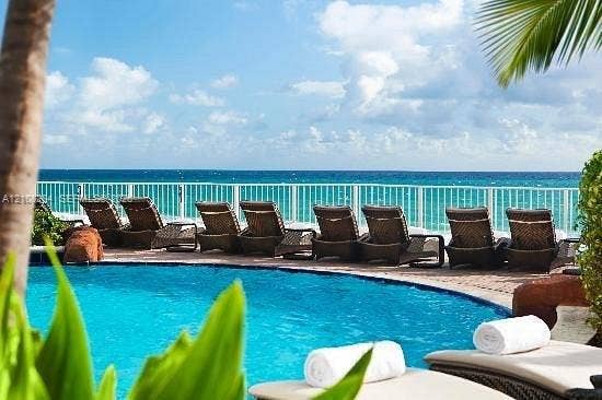 18001 Collins Avenue, #908, Sunny Isles Beach, FL 33160 Curved swimming pool with stone-accented hardscaping and a white metal perimeter railing