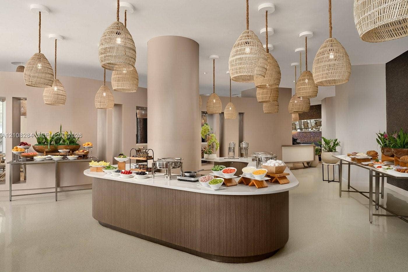 18001 Collins Avenue, #908, Sunny Isles Beach, FL 33160 Curved central island featuring a light-toned countertop and wood-finish cabinetry, illuminated by an array of woven pendant lighting, complemented by polished flooring