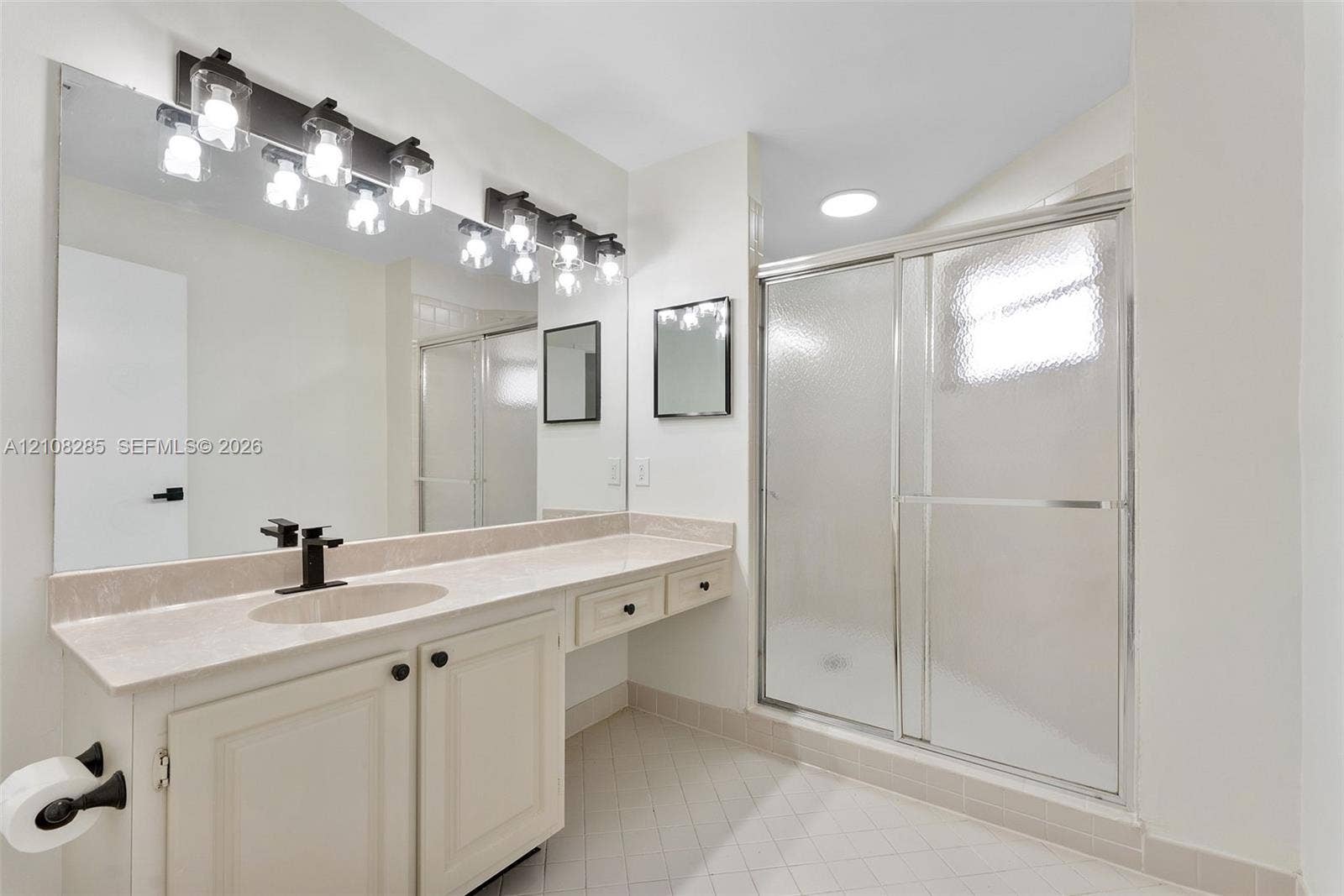 6626 Via Regina, #0, Boca Raton, Boca Raton, FL 33433 Bathroom featuring an expansive vanity with stone-style countertop, undermount sink with matte black faucet, wall-to-wall mirror, multi-light fixture, and glass-enclosed shower