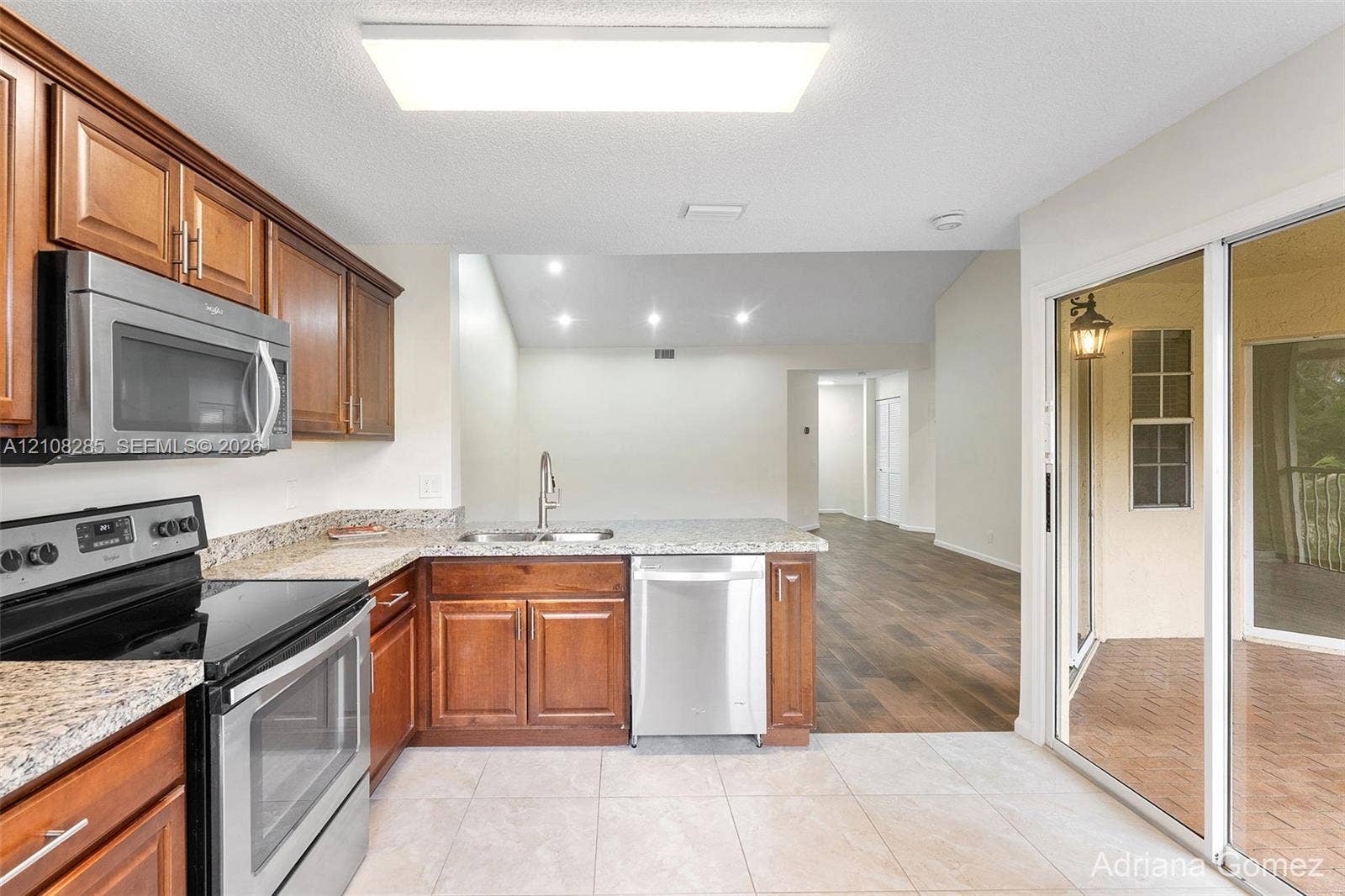 6626 Via Regina, #0, Boca Raton, Boca Raton, FL 33433 Kitchen featuring wood cabinetry, stone-finish countertops, stainless steel appliances, tile flooring, and sliding glass doors