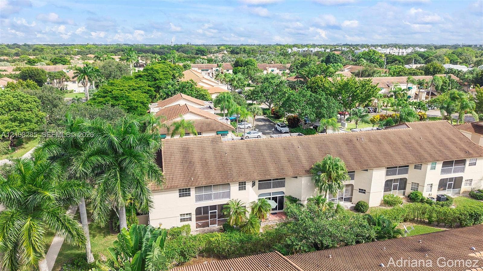 6626 Via Regina, #0, Boca Raton, Boca Raton, FL 33433 Multi-story residential building with a tile roof, light-colored stucco exterior, and screened-in lanais, set within a landscape of mature palm trees and greenery