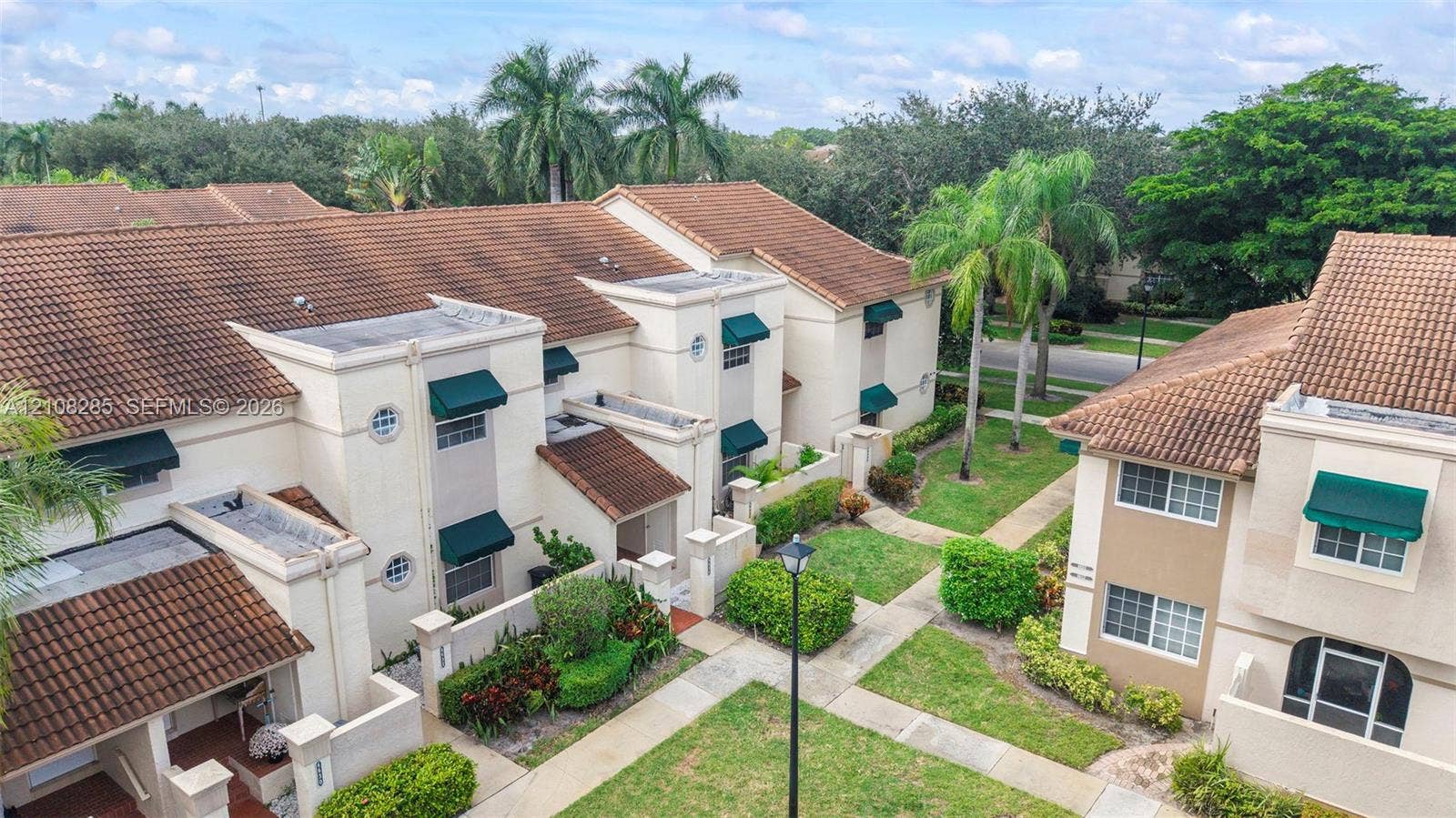6626 Via Regina, #0, Boca Raton, Boca Raton, FL 33433 Multi-story residential complex featuring terracotta-tiled roofs, stucco exterior finish, decorative green window awnings, and manicured landscaping throughout the grounds