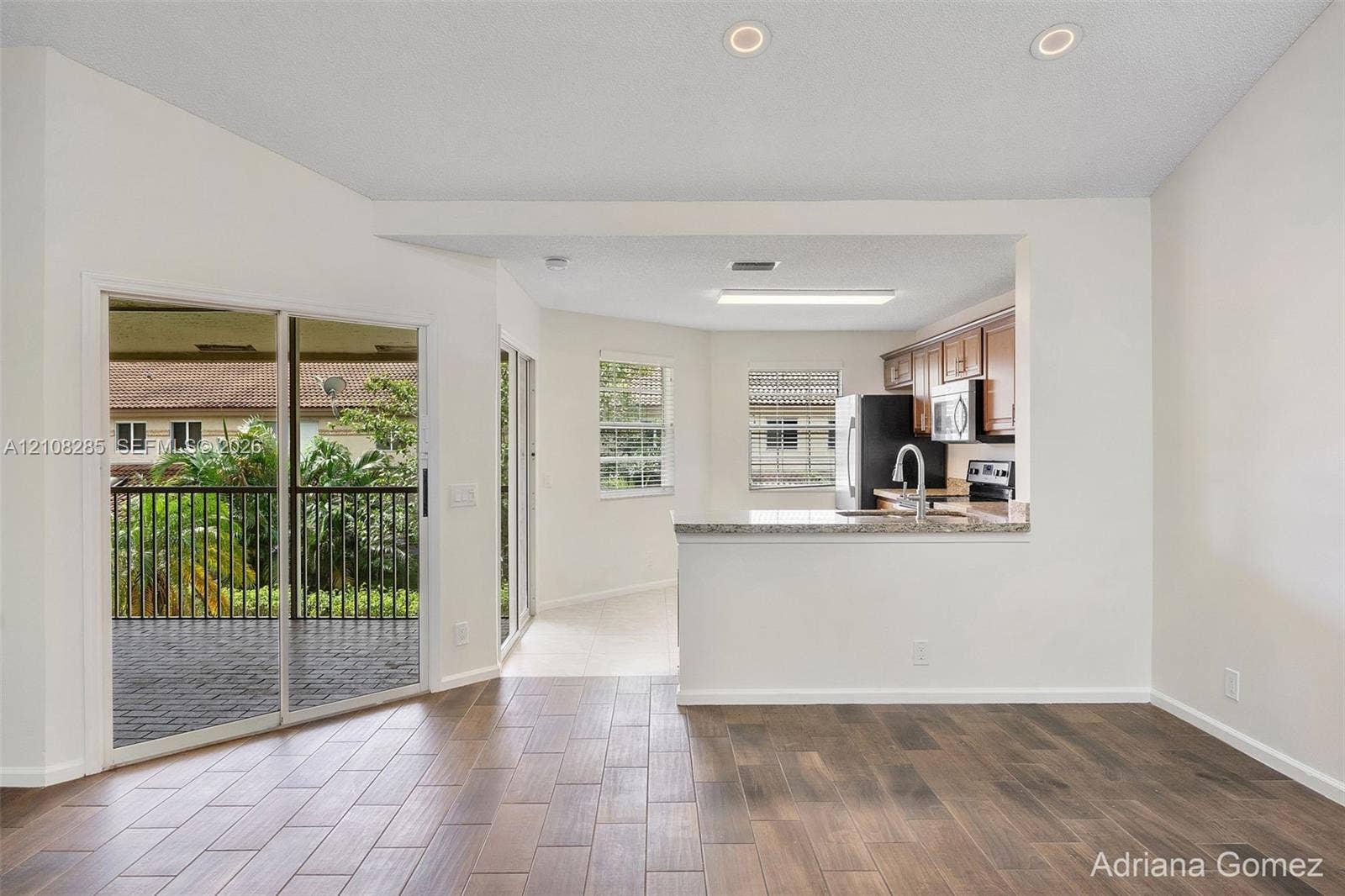 6626 Via Regina, #0, Boca Raton, Boca Raton, FL 33433 Kitchen featuring a stone-surface breakfast bar, wood-finish flooring, sliding glass doors, and recessed lighting