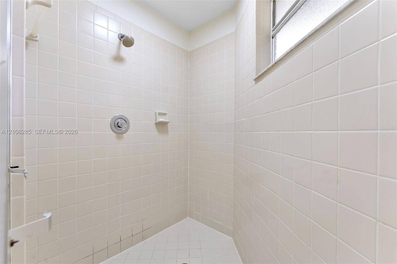 6626 Via Regina, #0, Boca Raton, Boca Raton, FL 33433 Shower stall featuring floor-to-ceiling square tile, a built-in soap niche, an integrated window, and a wall-mounted shower head with single-handle control