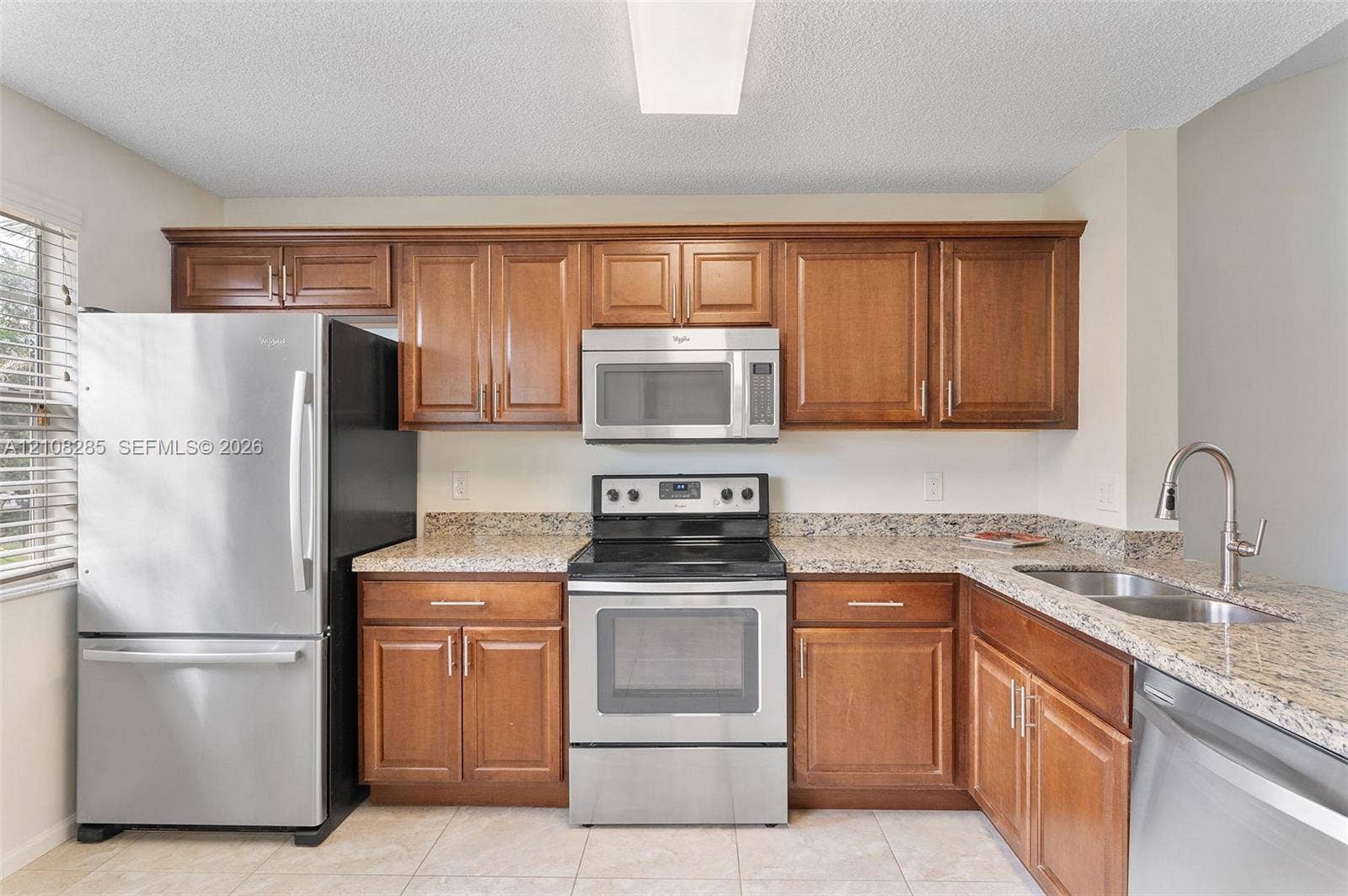 6626 Via Regina, #0, Boca Raton, Boca Raton, FL 33433 Kitchen featuring wooden cabinetry, stone-surface countertops, stainless steel appliances, a double-basin sink with a pull-down faucet, and tiled flooring