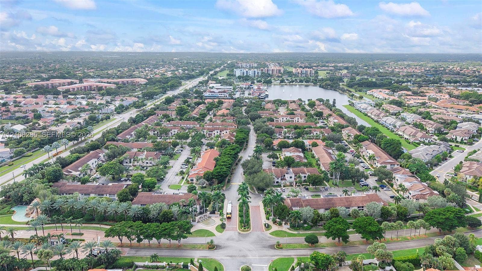 6626 Via Regina, #0, Boca Raton, Boca Raton, FL 33433 Aerial perspective featuring a residential community with paved roadways, tile-roofed structures, mature landscaping, and proximity to a central water feature
