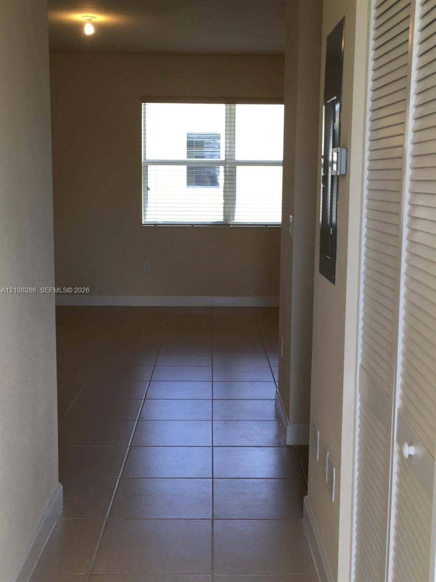 Interior space featuring large-format tile flooring, louvered bi-fold closet doors, and a multi-pane window with installed blinds