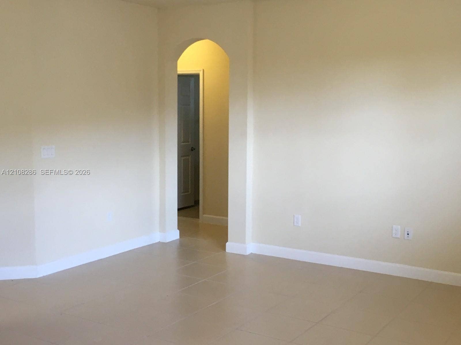 Neutral walls with arched doorway featuring classic architectural detailing and neutral-toned tile flooring