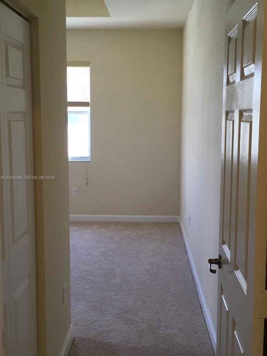 Neutral-toned room featuring neutral carpeting, a single-panel window with a blind, and six-panel interior doors
