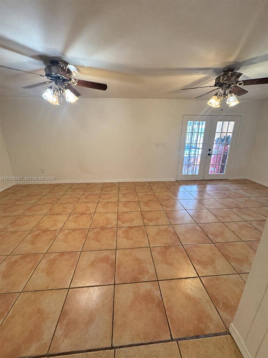 5350 NW 183rd Street, Miami Gardens, FL 33055 Large-format neutral tile flooring throughout, dual ceiling fans with multi-light fixtures, and white-paned French doors