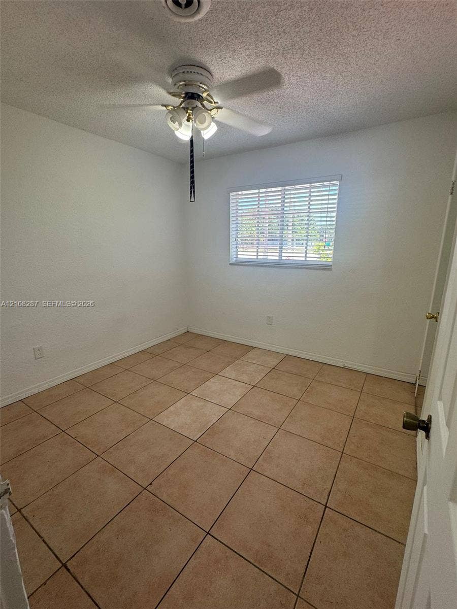 5350 NW 183rd Street, Miami Gardens, FL 33055 Neutral-toned tile flooring, ceiling fan with integrated multi-bulb light fixture, and horizontal window blinds