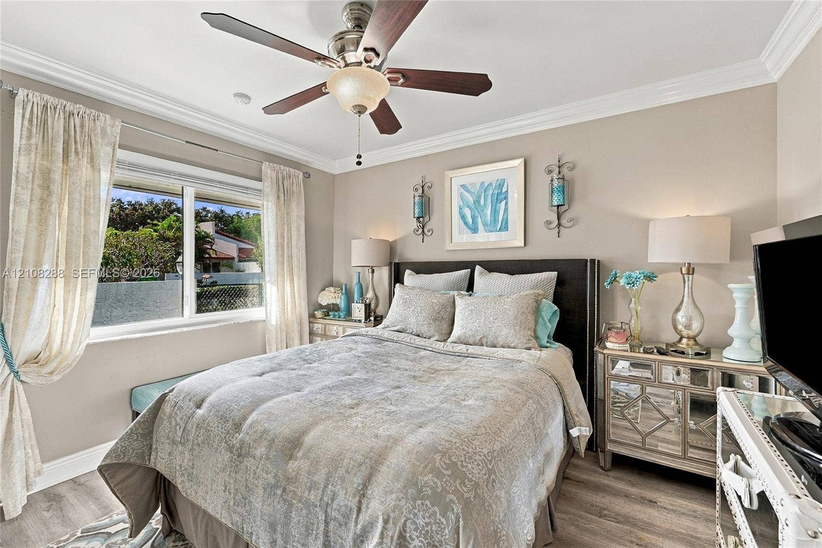 8292 NW 36th Street, Sunrise, FL 33351 Neutral-toned 2nd bedroom featuring wood-finish flooring, crown molding, and a multi-blade ceiling fan with an integrated light fixture