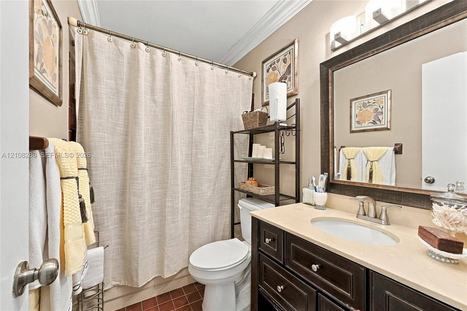 8292 NW 36th Street, Sunrise, FL 33351 Guest Bathroom featuring a vanity with dark-finish cabinetry, a light-toned countertop, and an undermount oval sink, complemented by a framed wall mirror, crown molding, and tiled flooring