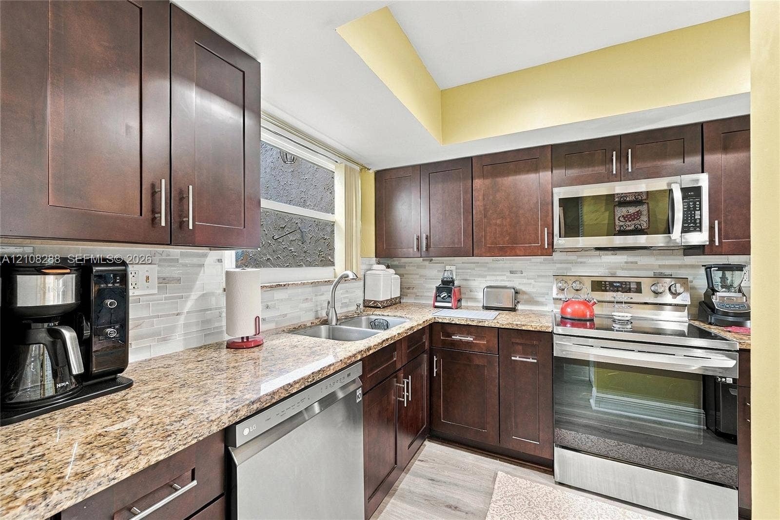 8292 NW 36th Street, Sunrise, FL 33351 Kitchen featuring dark-toned cabinetry, stone-finish countertops, stainless steel appliances, light-toned horizontal tile backsplash, and light-toned hard-surface flooring