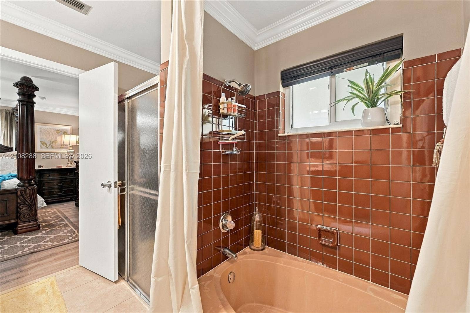 8292 NW 36th Street, Sunrise, FL 33351 Bathroom featuring a sunken cultured marble Roman tub, floor-to-ceiling high-gloss terracotta wall tile, integrated shower enclosure with a frosted glass door, and a horizontal window with a dark trim finish