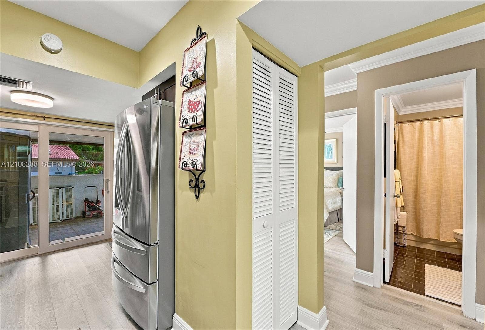 8292 NW 36th Street, Sunrise, FL 33351 Stainless steel French door refrigerator, wood-finish flooring, white louvered-door closet, and glass sliding door featuring an exterior balcony