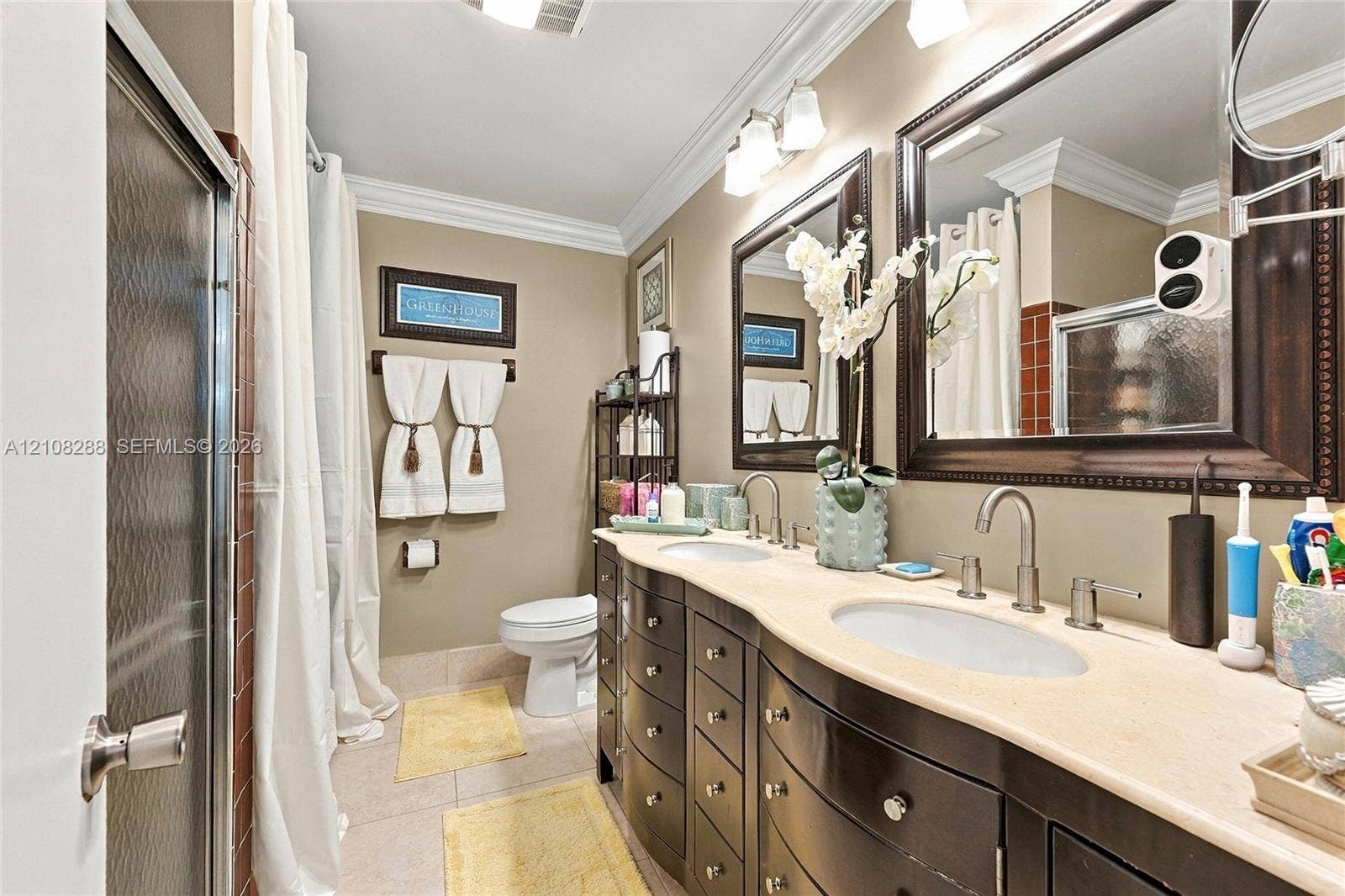8292 NW 36th Street, Sunrise, FL 33351 Dual-sink vanity with dark-finish cabinetry, stone countertop, two framed mirrors, and crown molding