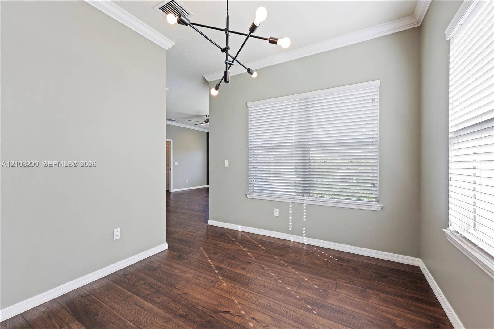 Interior space featuring wood-finish flooring, crown molding, a modern multi-arm sputnik chandelier, and horizontal window blinds