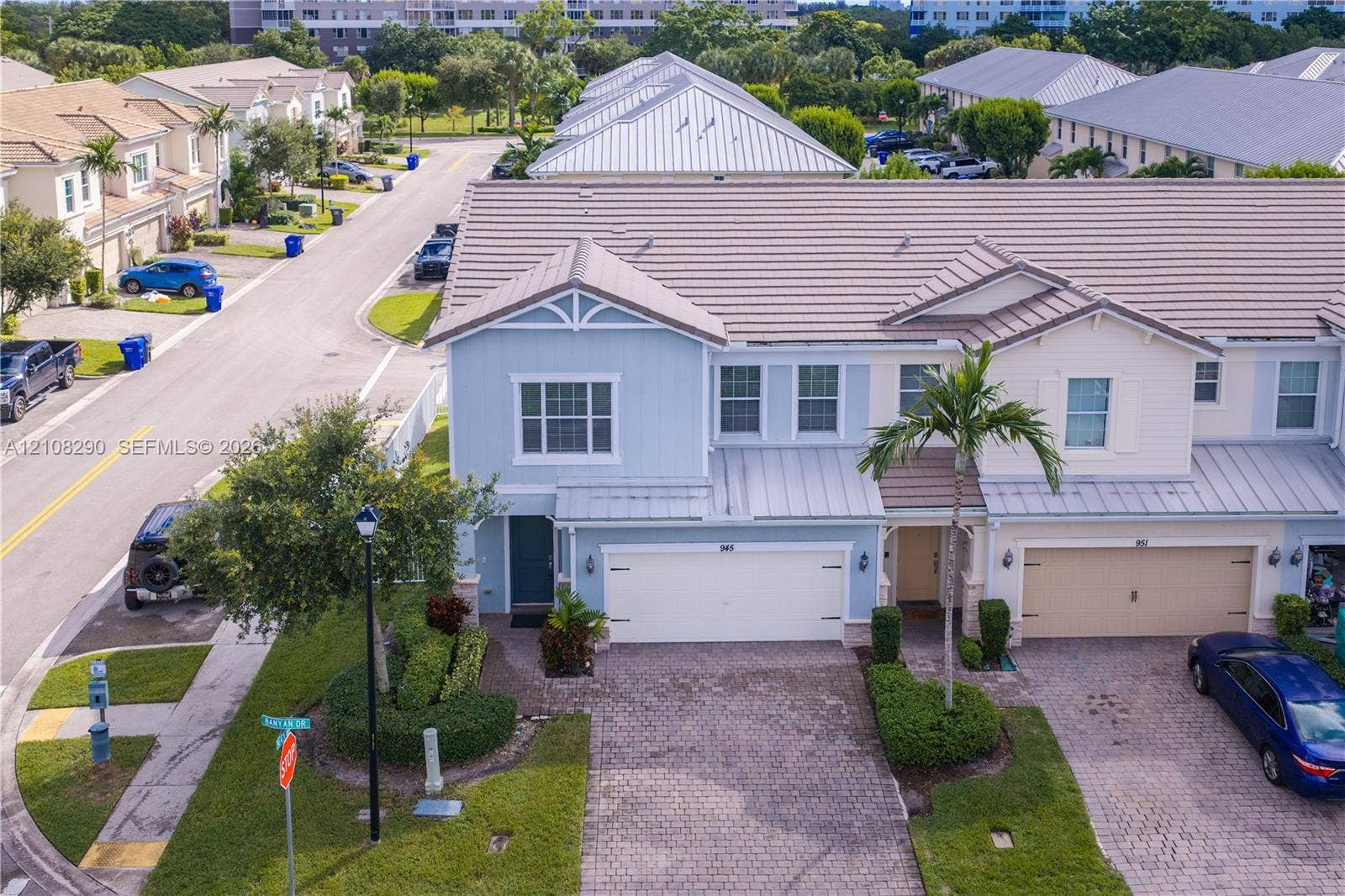 Multi-story exterior featuring a tile roof, lap siding, a two-car garage, and a paver driveway