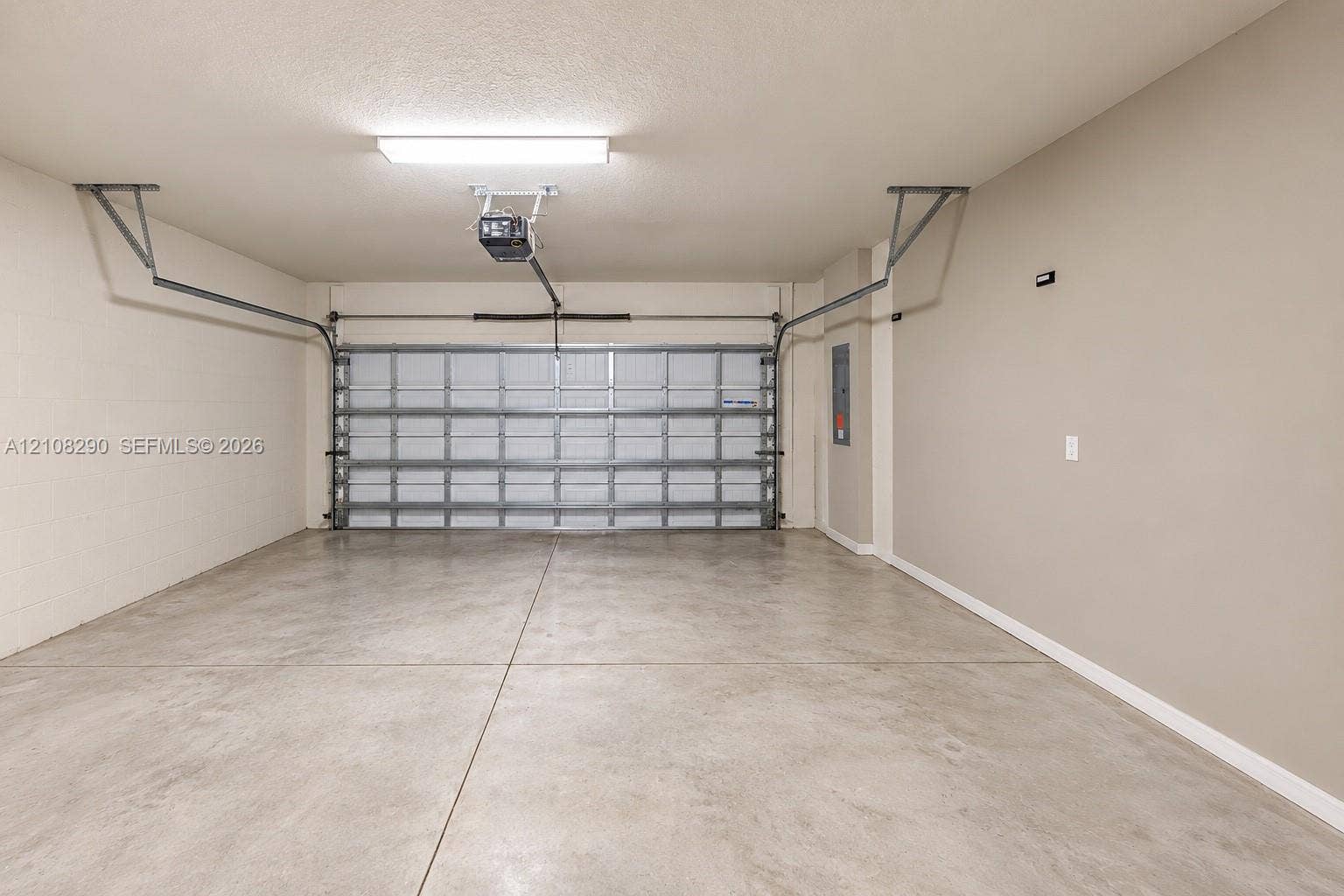 Two-car garage featuring a concrete floor, finished walls, overhead lighting, and an automated door opener