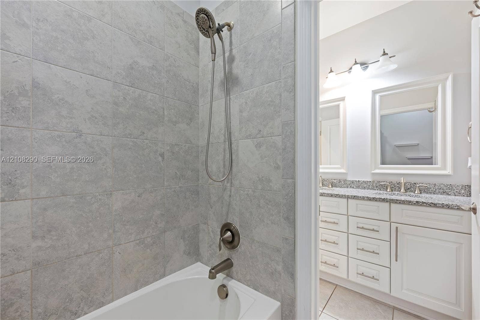 Shower area featuring stone-look wall tile and a multi-setting handheld showerhead