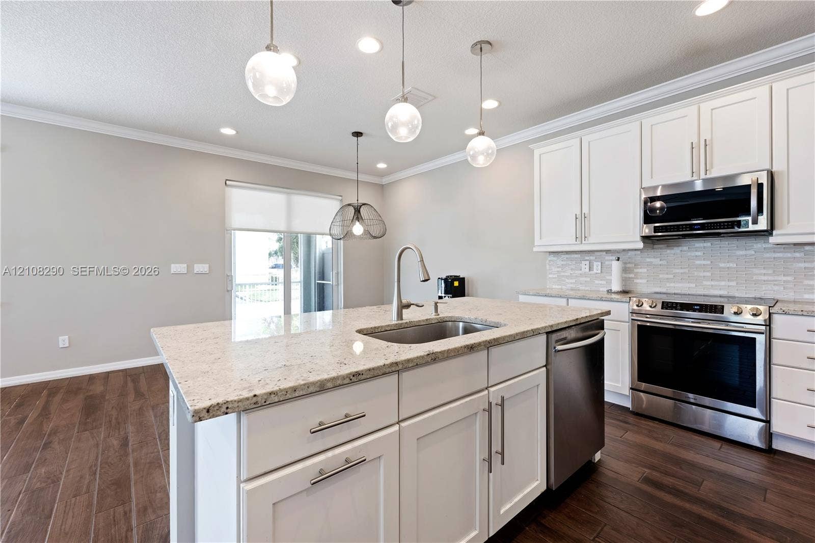Kitchen featuring white shaker-style cabinetry, stone countertops, stainless steel appliances, wood-finish flooring, and multi-pendant lighting