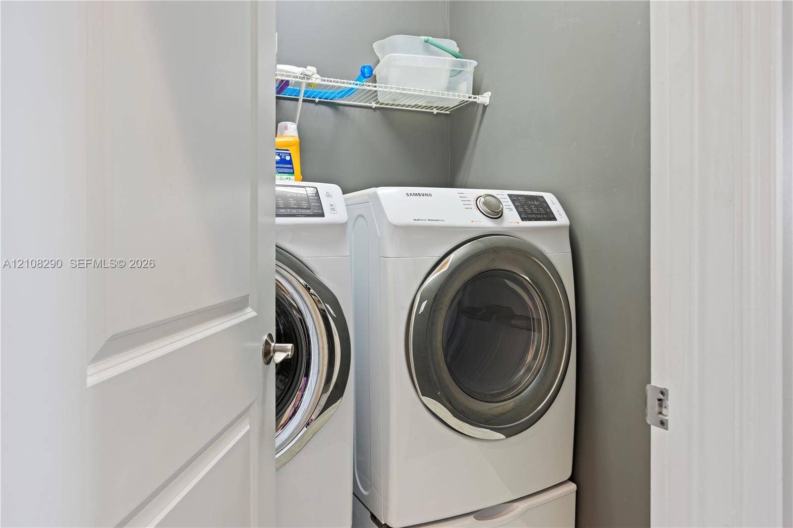 Laundry area featuring a side-by-side washer and dryer set with pedestal bases and a mounted wire shelving unit