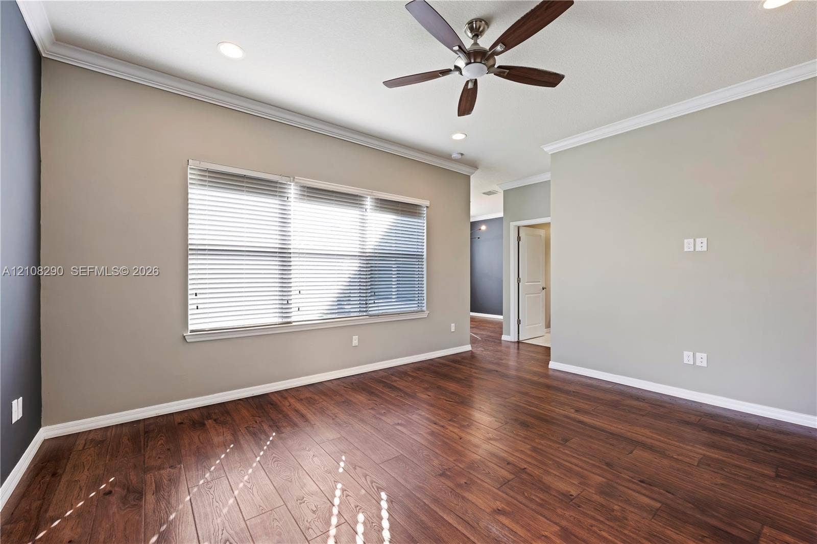 Spacious room featuring wood-finish flooring, crown molding, recessed lighting, and a ceiling fan with integrated lighting