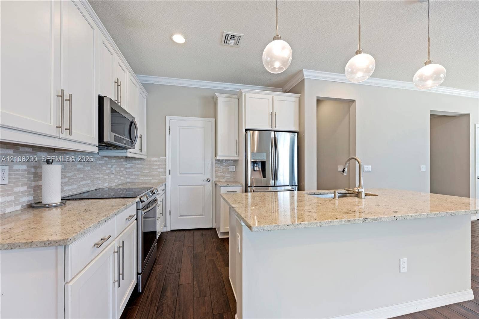 Kitchen featuring white shaker-style cabinetry, stone countertops, stainless steel appliances, decorative glass pendant lighting, and wood-finish flooring