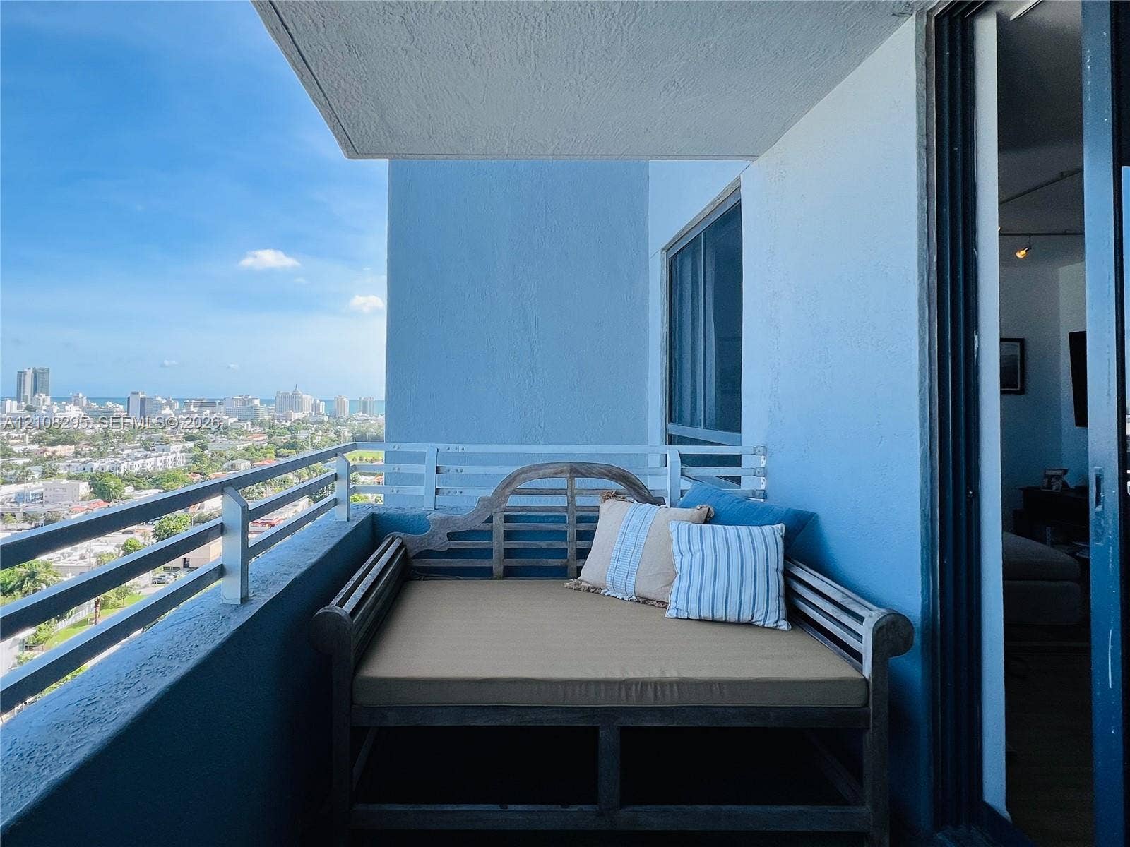 Private balcony with a metal horizontal railing, featuring a concrete ceiling and expansive cityscape scenery