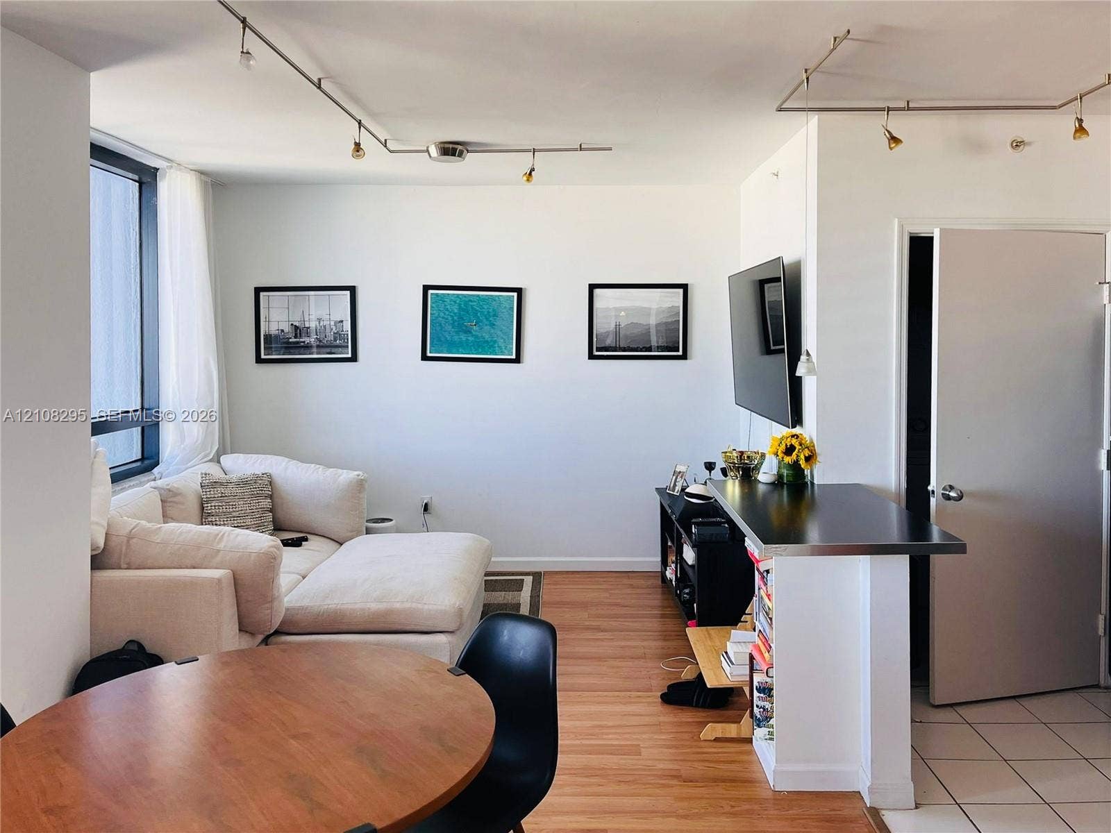 Living space featuring wood-finish flooring, floor-to-ceiling windows, built-in breakfast bar with metallic countertop, and adjustable track lighting
