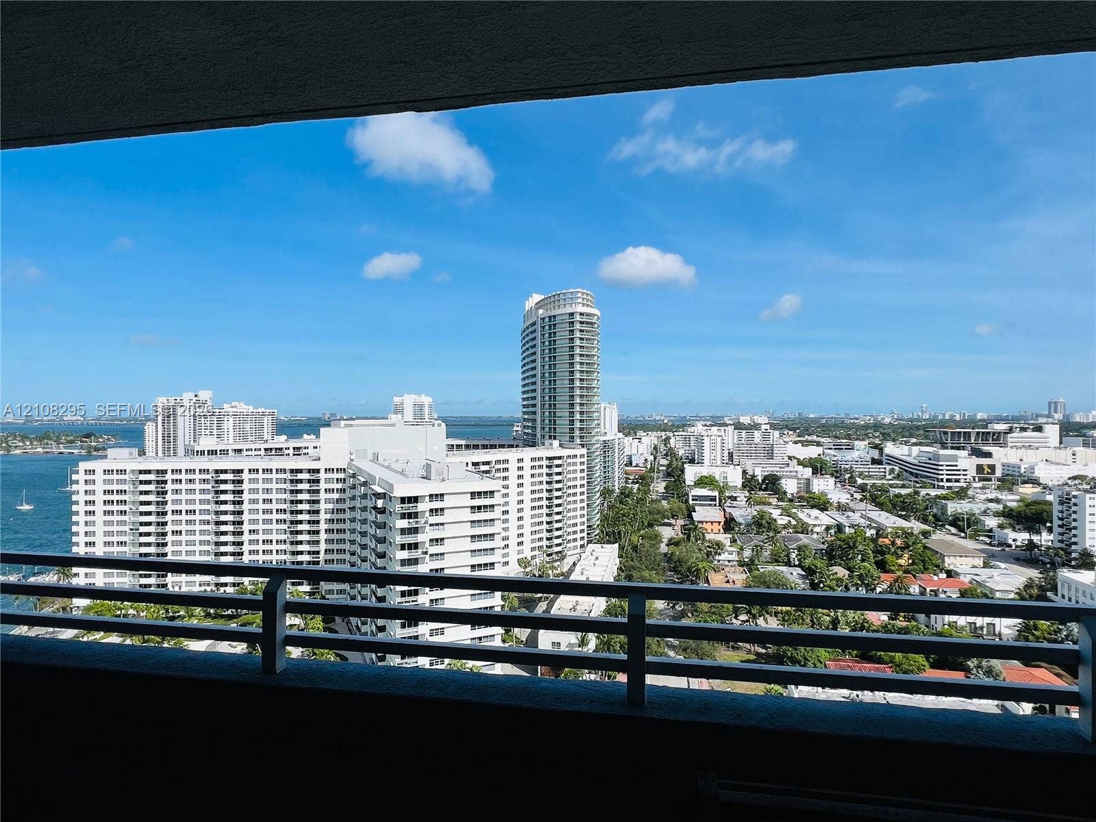 Covered balcony with a metal railing, providing an expansive outlook over the urban skyline and adjacent waterway