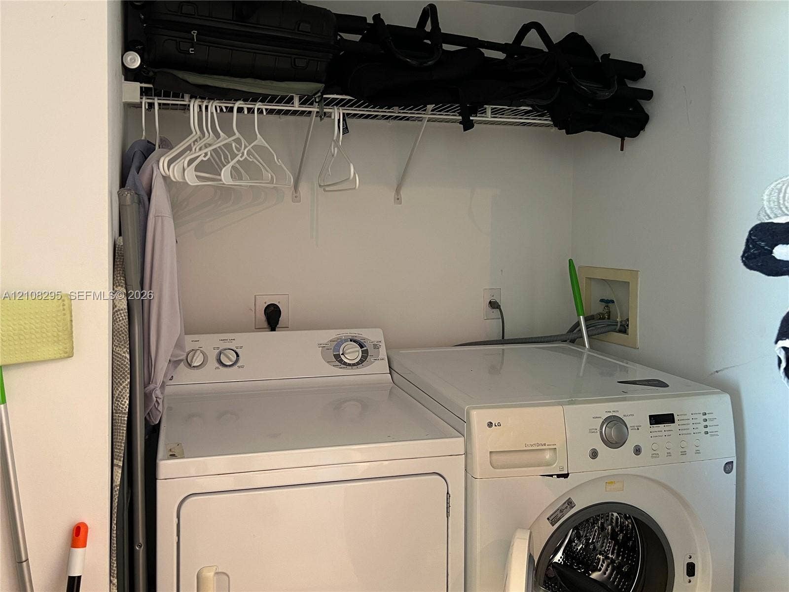 Dedicated laundry area featuring a white front-load washer and a top-load dryer, complemented by a white wire overhead shelving system