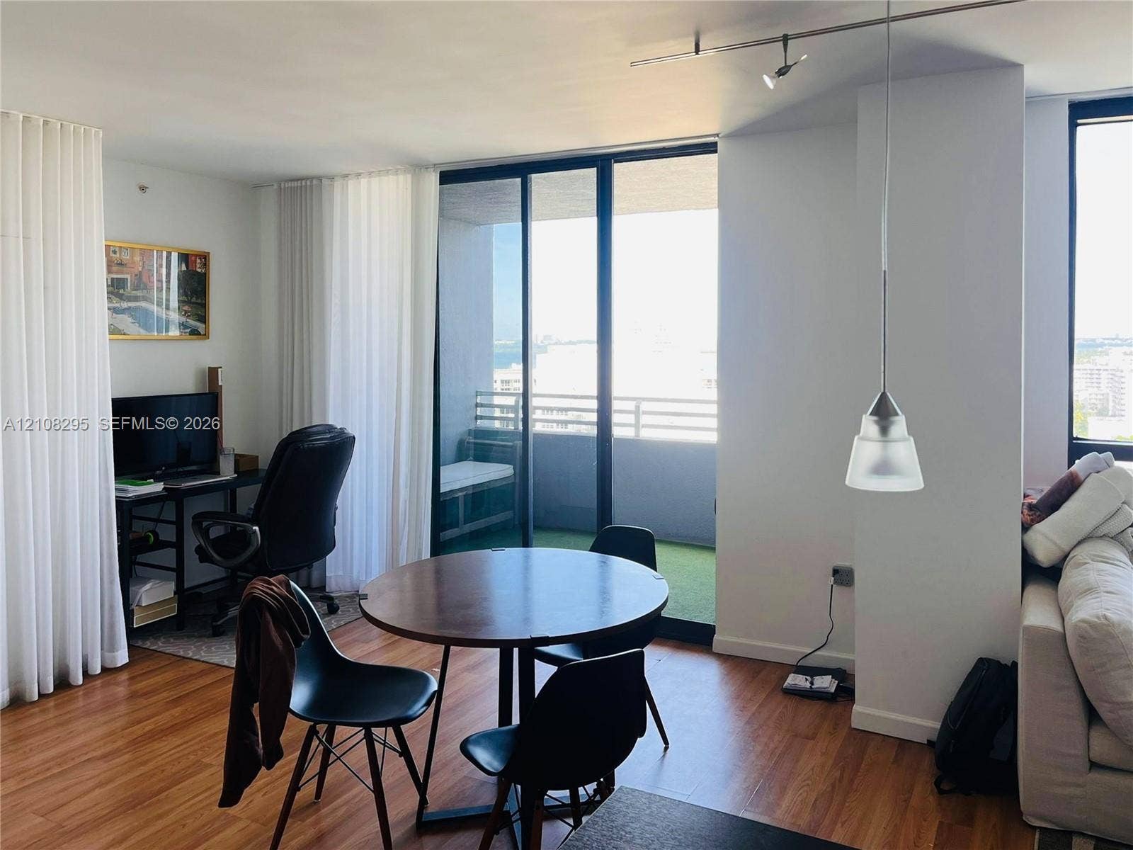Living space featuring wood-finish flooring, floor-to-ceiling sliding glass doors, a private balcony, pendant lighting, and track lighting