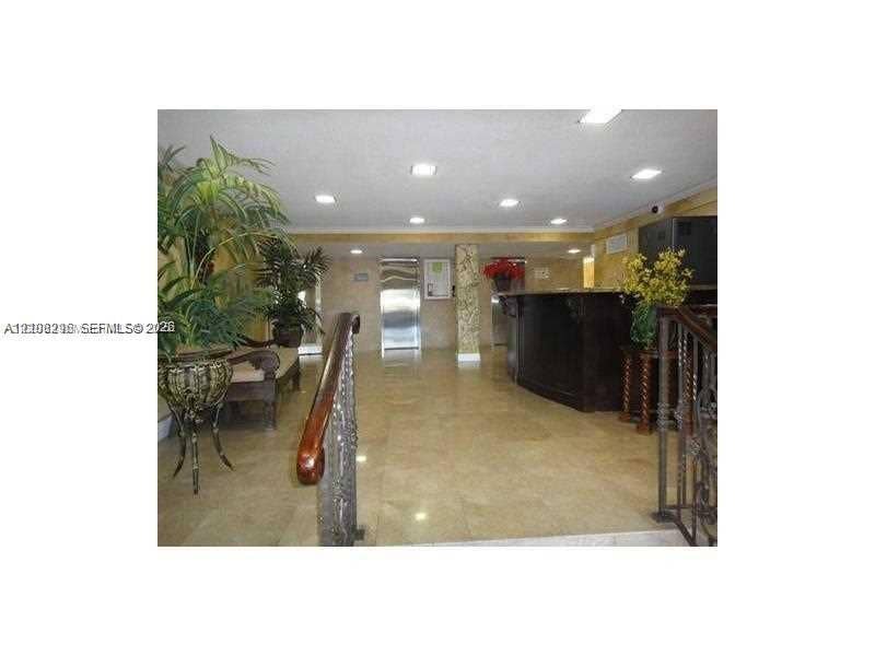 1800 Sans Souci Boulevard, #340, North Miami, North Miami, FL 33181 Lobby featuring polished stone tile flooring, recessed ceiling lighting, a dark-toned service desk, metal elevator doors, and a wrought iron stair railing