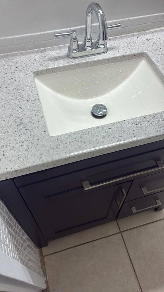 1800 Sans Souci Boulevard, #340, North Miami, North Miami, FL 33181 Dark-toned vanity cabinet featuring metallic bar hardware, solid-surface countertop with an integrated basin, high-arc faucet, and tiled backsplash